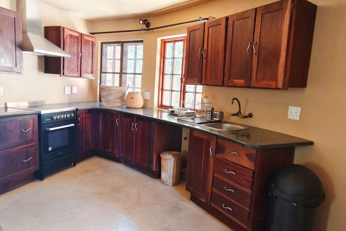 A functional kitchen featuring dark wood cabinetry, granite countertops, a stainless steel extractor fan, and a freestanding oven.