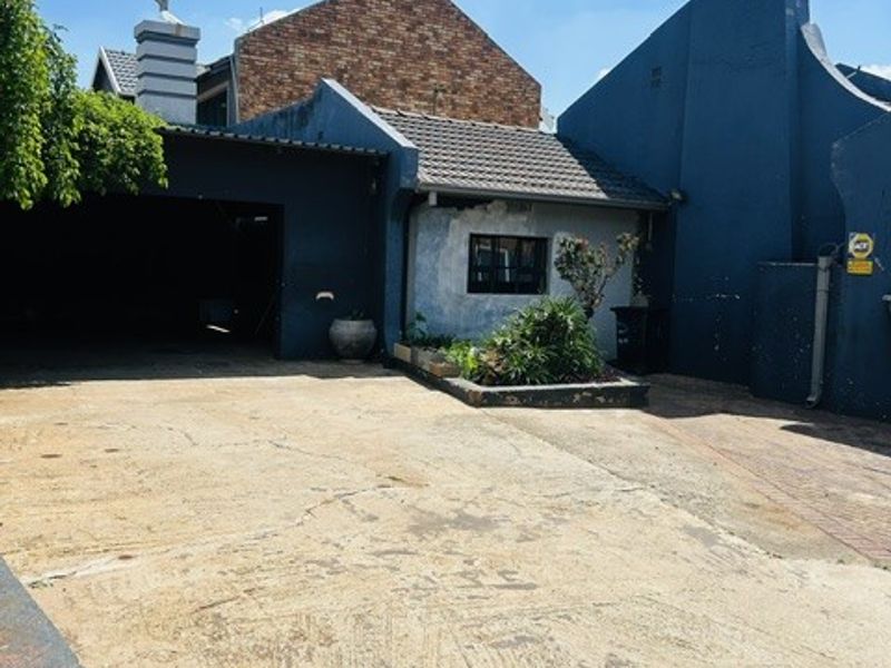 Front exterior view of the property featuring a concrete driveway, attached garage, and a raised garden bed against the building facade.