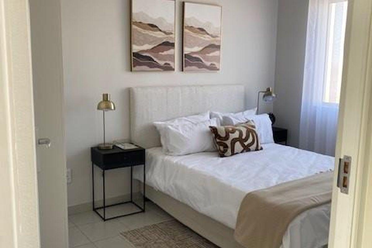 A well-maintained bedroom featuring neutral wall tones, tiled flooring, and a built-in cupboard, offering a clean and comfortable living space.