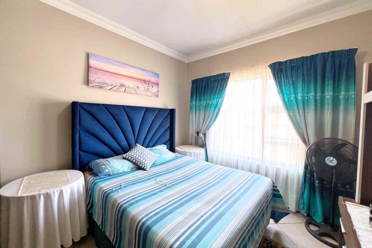 A well-maintained bedroom featuring neutral wall tones, crown molding, and tiled flooring, providing a comfortable and functional living space.