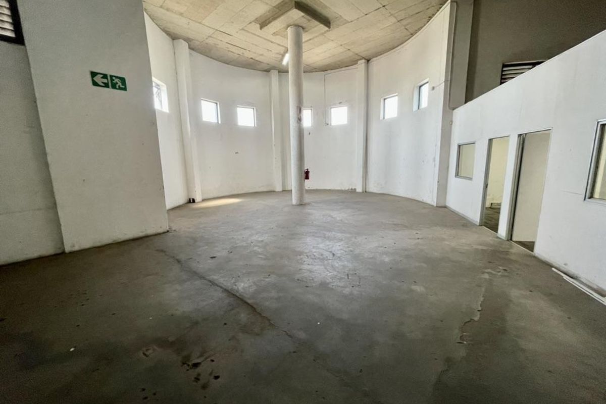 A spacious, empty industrial utility area featuring a central support column, exposed concrete ceiling, and polished concrete flooring with visible wear.