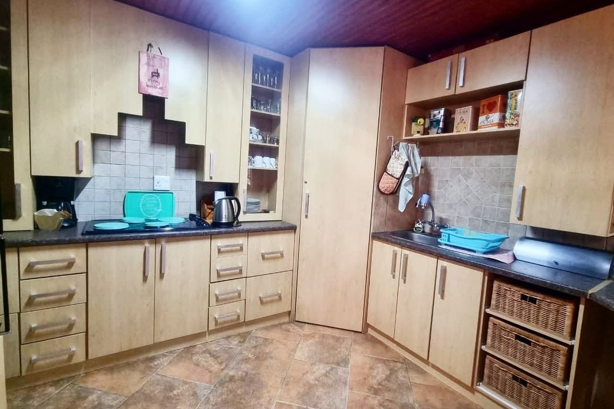 A functional kitchen featuring light wood-finish cabinetry, tiled backsplash, laminate countertops, and integrated sink, offering a practical layout for daily meal preparation.