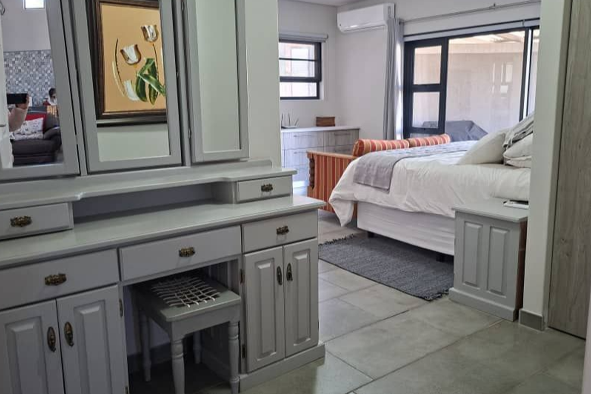 Spacious bedroom featuring tiled flooring, built-in cabinetry, a split-system air conditioner, and sliding glass doors providing access to the exterior.