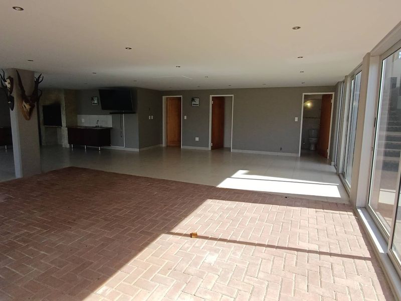 Spacious open-plan living area featuring a mix of brick and tile flooring, built-in bar, and large sliding glass doors providing ample natural light.