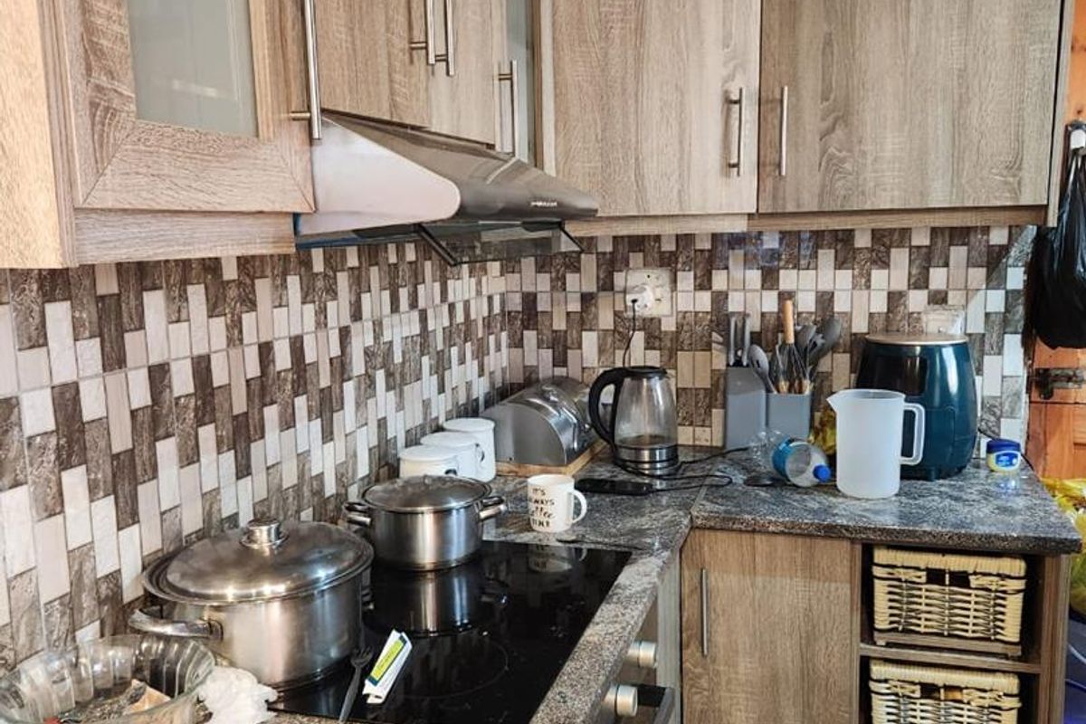 A functional kitchen featuring wood-look cabinetry, granite-effect countertops, a mosaic tile backsplash, and built-in cooking appliances.