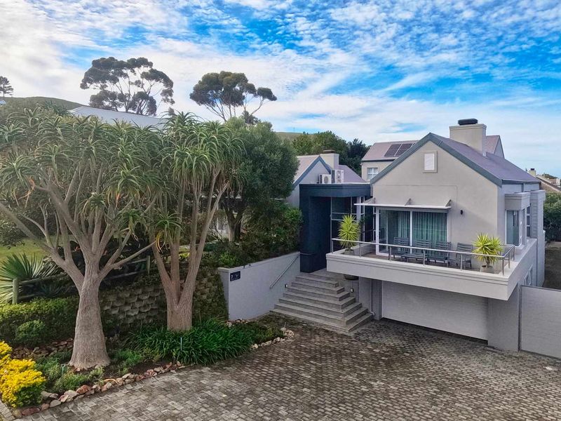 A well-maintained multi-level residential property featuring a paved driveway, integrated garage, and an elevated balcony with modern balustrades.