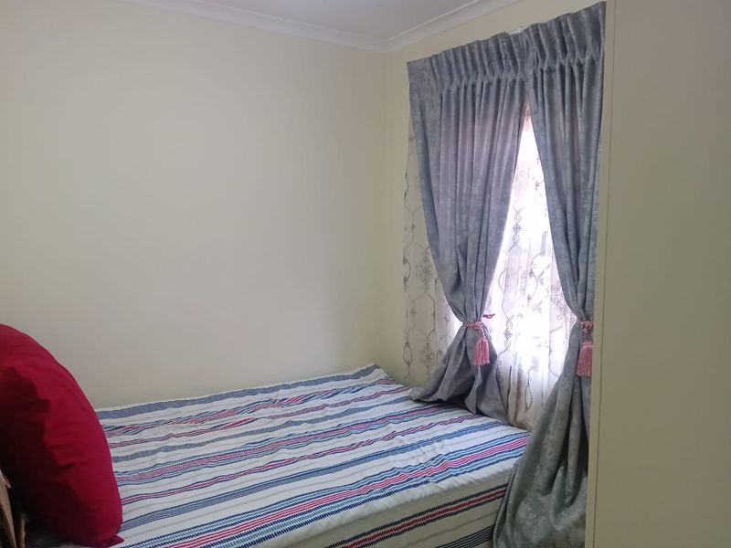 A standard bedroom featuring neutral walls and a window with curtains.