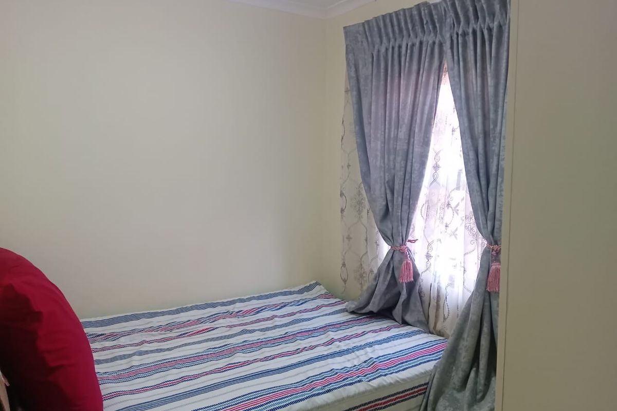 A standard bedroom featuring neutral walls and a window with curtains.