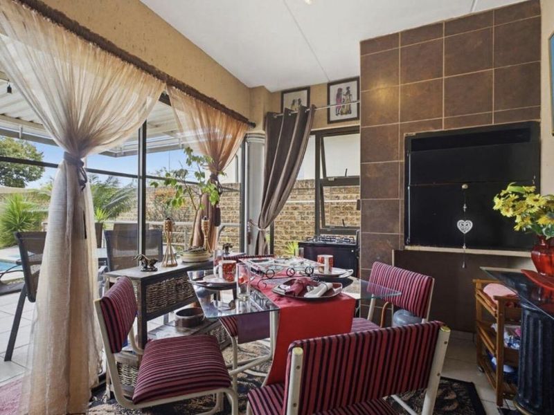 Covered patio area featuring a built-in braai, tiled flooring, and large sliding glass doors providing access to the outdoor pool area.
