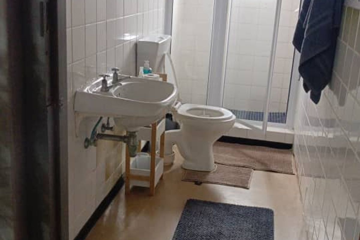 A functional bathroom featuring a wall-mounted basin, toilet, and a separate shower enclosure with tiled wall finishes.