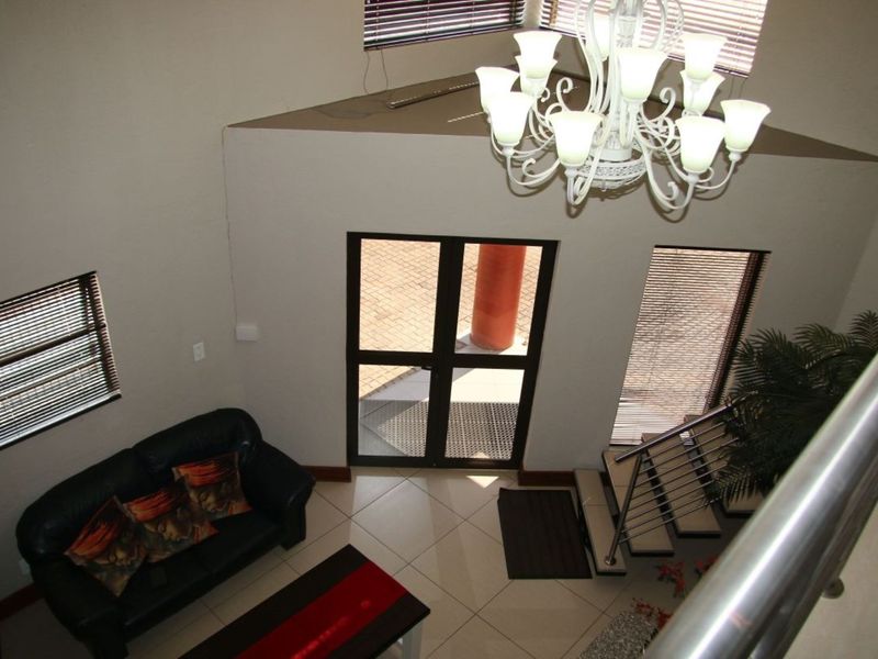 High-ceiling entrance foyer featuring tiled flooring, a feature chandelier, and a staircase with a modern metal balustrade leading to the upper level.