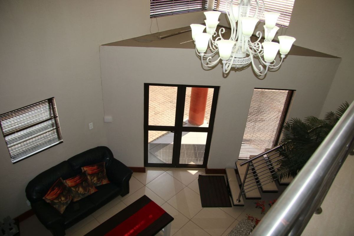 High-ceiling entrance foyer featuring tiled flooring, a feature chandelier, and a staircase with a modern metal balustrade leading to the upper level.