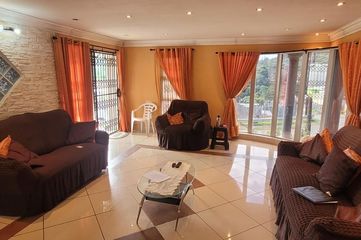 Spacious living room featuring large windows, tiled flooring, recessed lighting, and a decorative stone feature wall.