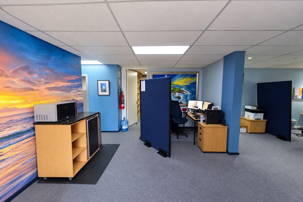 An open-plan office space featuring a suspended ceiling, recessed lighting, and a dedicated kitchenette area with a mural wall.