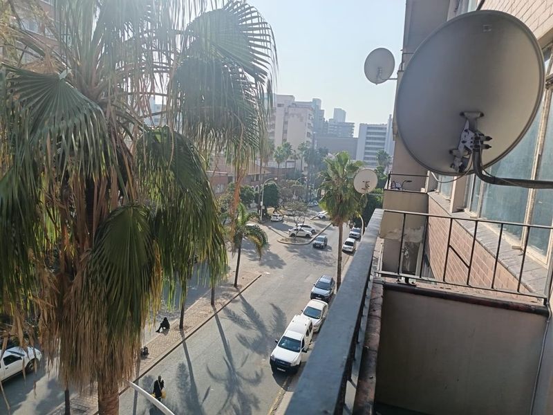 A balcony view overlooking a city street, featuring a metal railing and mounted satellite dishes.