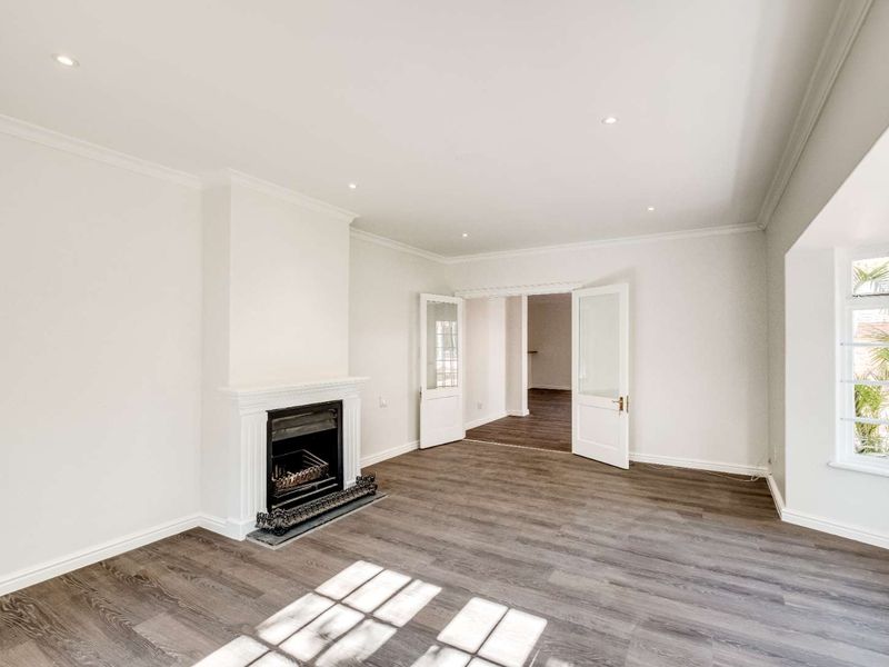 Spacious living room featuring a classic fireplace, laminate flooring, recessed lighting, and elegant french doors leading to an adjoining space.