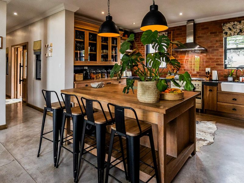 A stylish kitchen featuring an island, exposed brick wall, farmhouse sink, and polished concrete floors, creating a warm and industrial aesthetic.