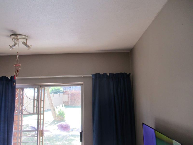 A living room area featuring a sliding glass door with security gate, providing access to the outdoor space.