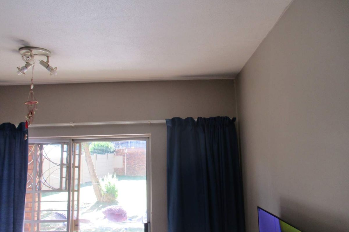 A living room area featuring a sliding glass door with security gate, providing access to the outdoor space.