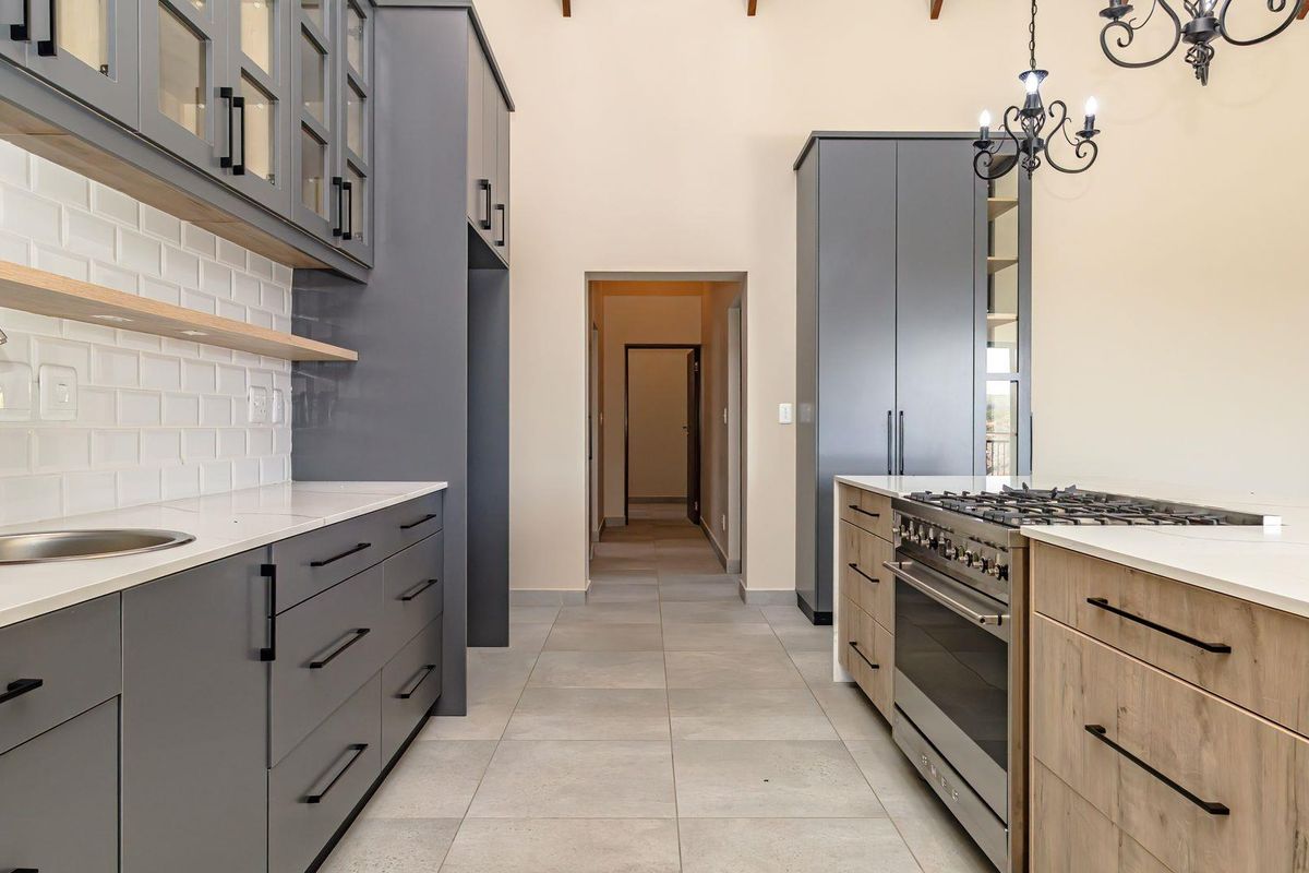 Modern kitchen featuring grey cabinetry, white stone countertops, subway tile backsplash, and a central island with a built-in gas stove.