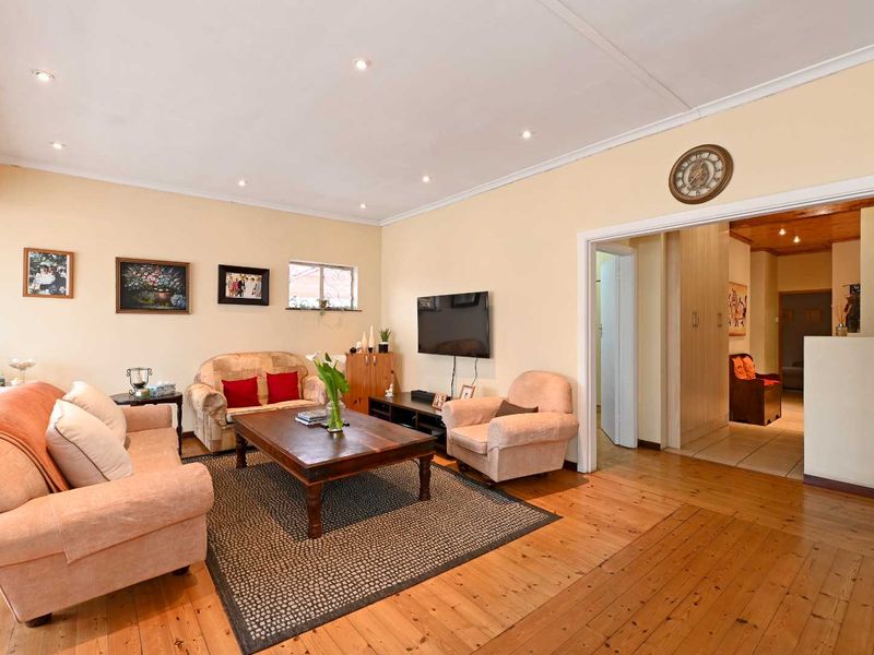 A spacious living room featuring warm timber flooring, recessed downlighting, and neutral wall finishes, providing a comfortable and inviting atmosphere.