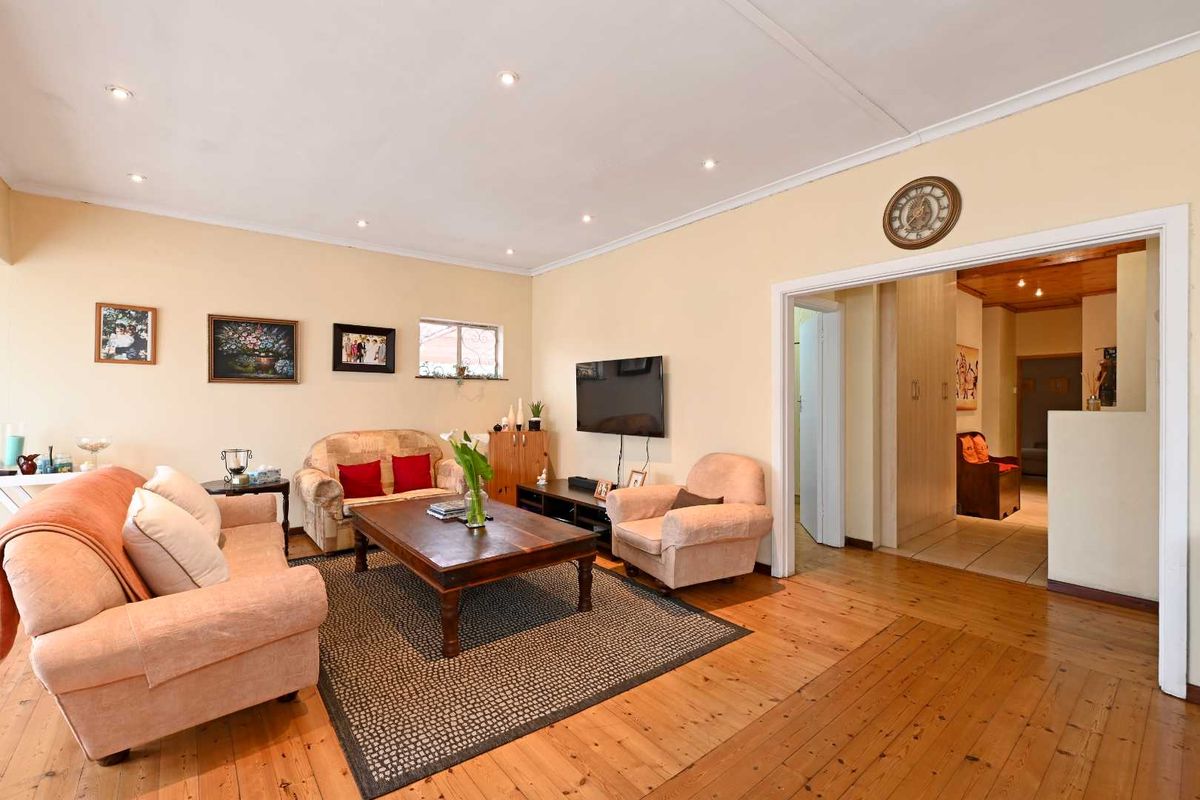 A spacious living room featuring warm timber flooring, recessed downlighting, and neutral wall finishes, providing a comfortable and inviting atmosphere.