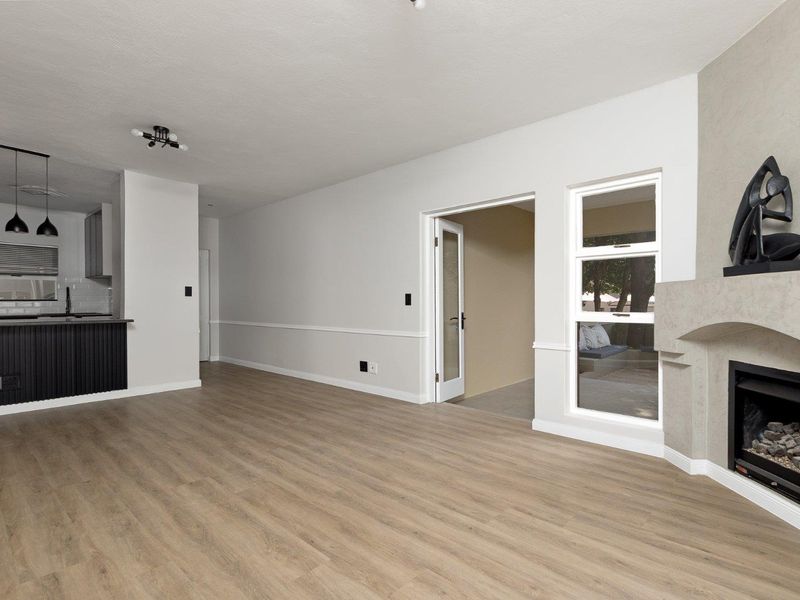 Spacious open-plan living area featuring modern laminate flooring, a built-in fireplace, and a sleek kitchen with island seating and contemporary pendant lighting.
