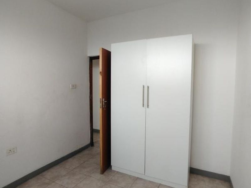 A simple bedroom featuring tiled flooring and a built-in wardrobe, offering a functional space ready for personalization.