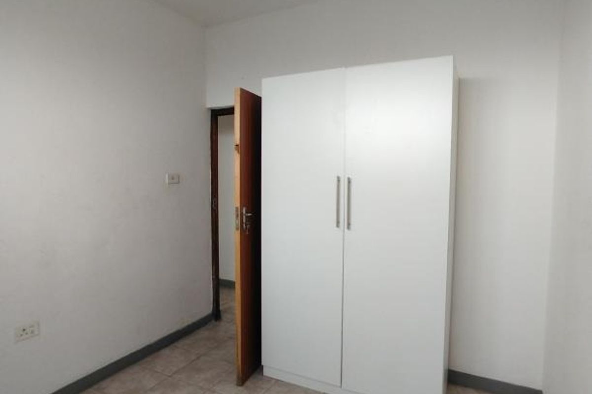 A simple bedroom featuring tiled flooring and a built-in wardrobe, offering a functional space ready for personalization.