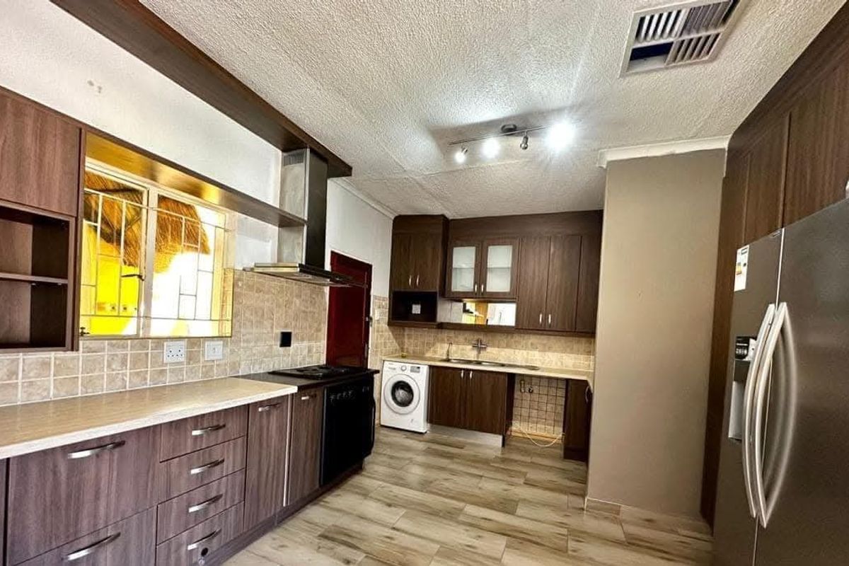 A functional kitchen featuring dark wood cabinetry, laminate countertops, tiled backsplash, and integrated appliances, offering a practical layout for daily meal preparation.