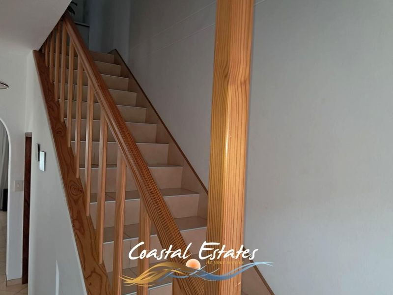 A functional interior hallway featuring a wooden staircase with a matching balustrade and tiled stair treads.