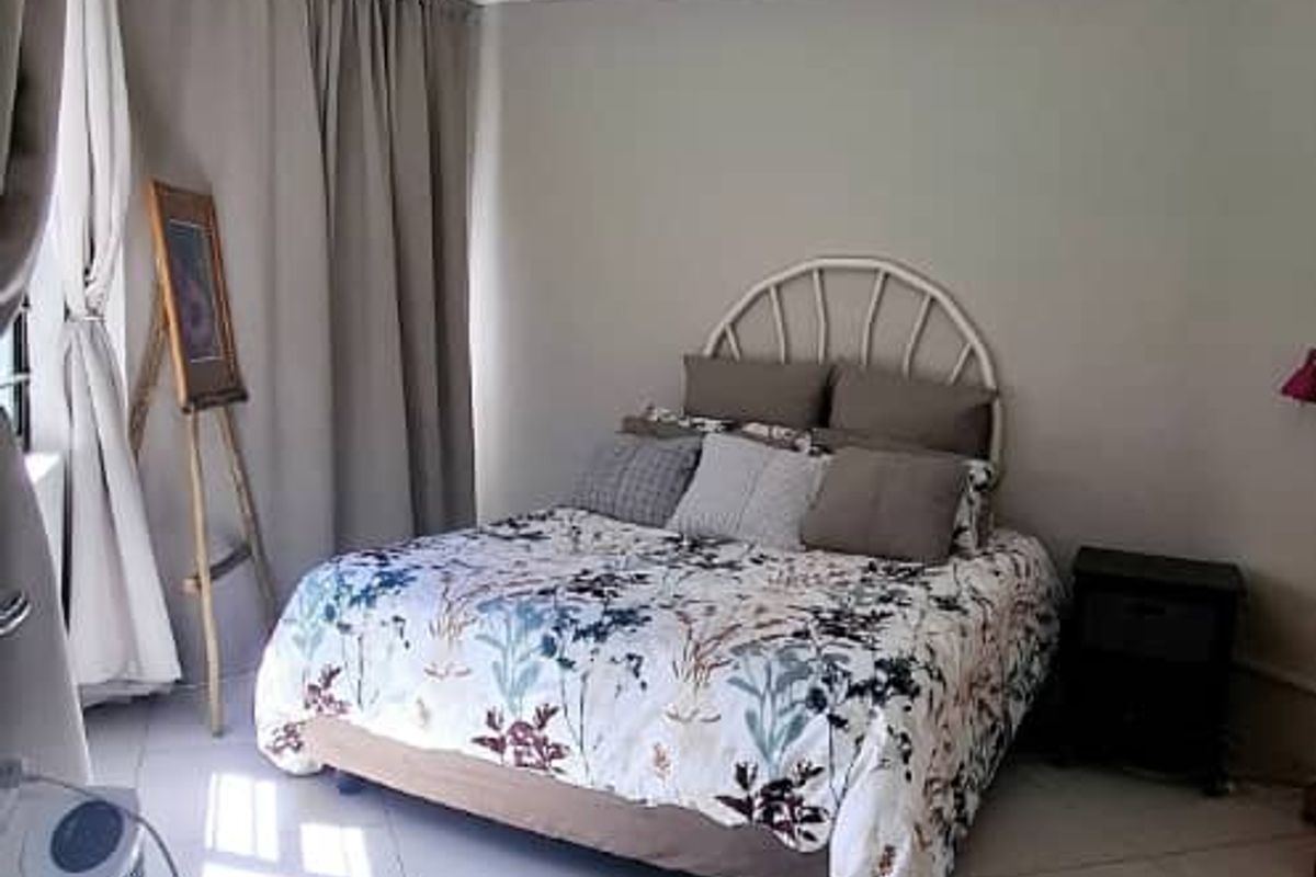 A bedroom featuring neutral wall tones, tiled flooring, and a ceiling fan, providing a functional and comfortable sleeping space.