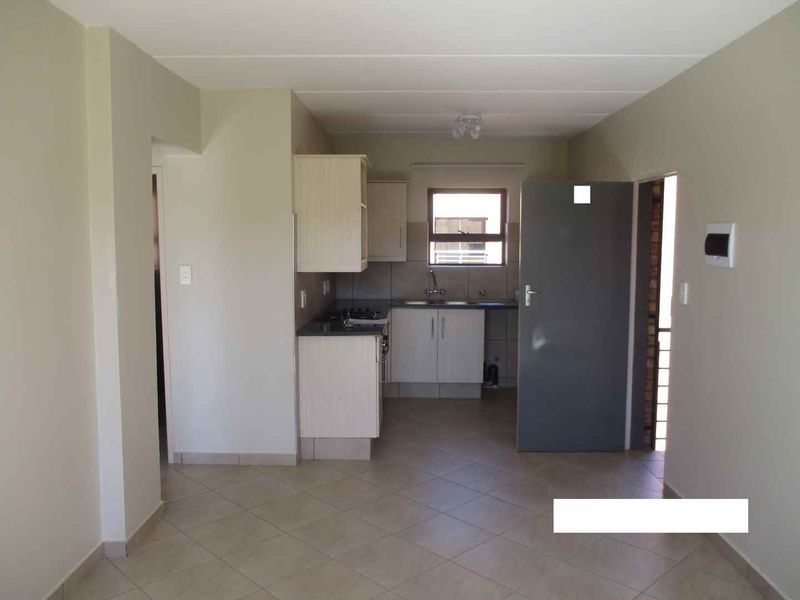 An open-plan living and kitchen area featuring tiled flooring and functional built-in cabinetry with a stainless steel sink.