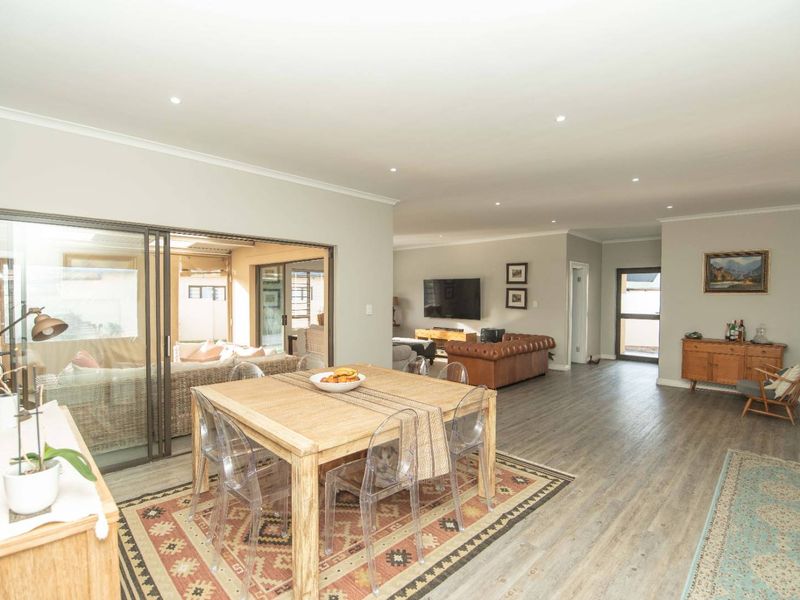 Spacious open-plan living and dining area featuring modern laminate flooring, recessed downlighting, and large sliding glass doors providing seamless access to the patio.