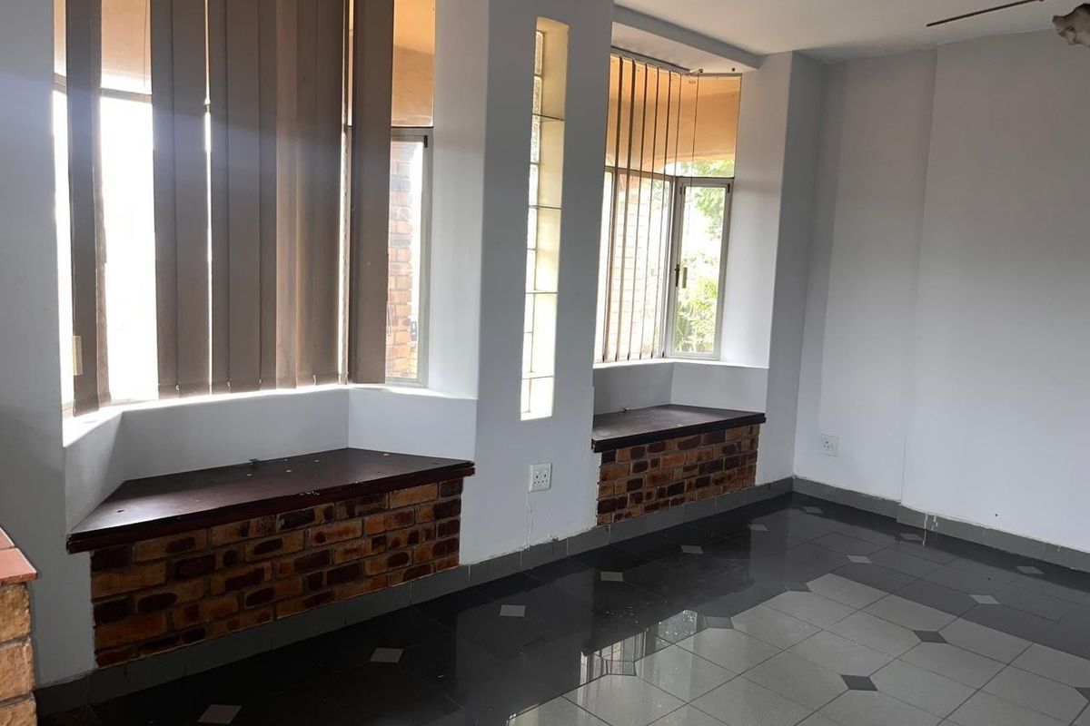An empty living area featuring unique brick-faced window seats, glass block accents, and dark tiled flooring with a ceiling fan.