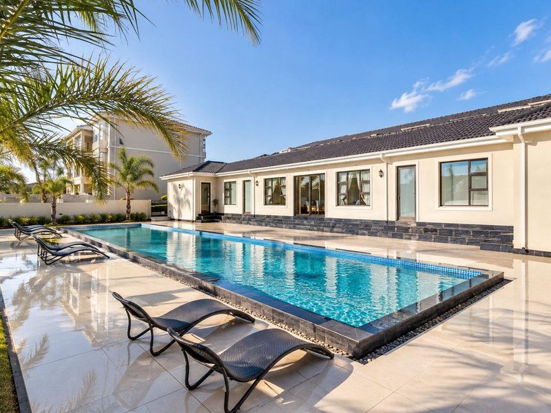 A well-maintained outdoor pool area featuring a modern swimming pool, tiled deck, and direct access to the apartment through sliding glass doors.
