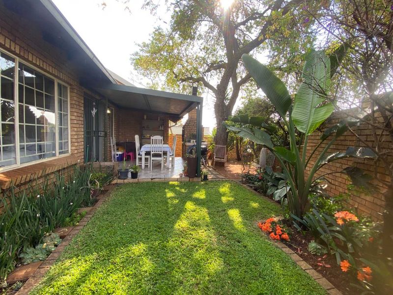 A private rear garden featuring a covered patio area, established landscaping, and brick boundary walls, providing a pleasant outdoor living space.
