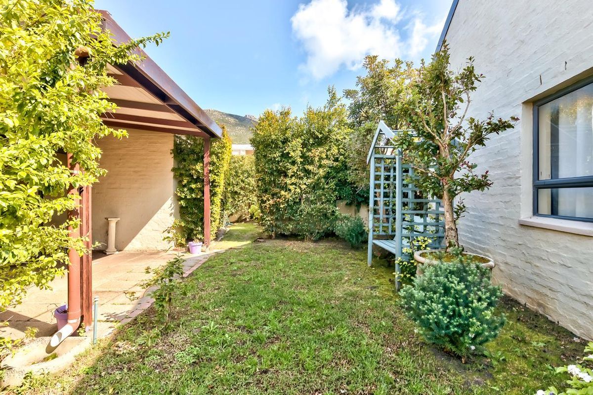 A private rear garden featuring a covered patio area, established landscaping, and a well-maintained lawn adjacent to the main building structure.