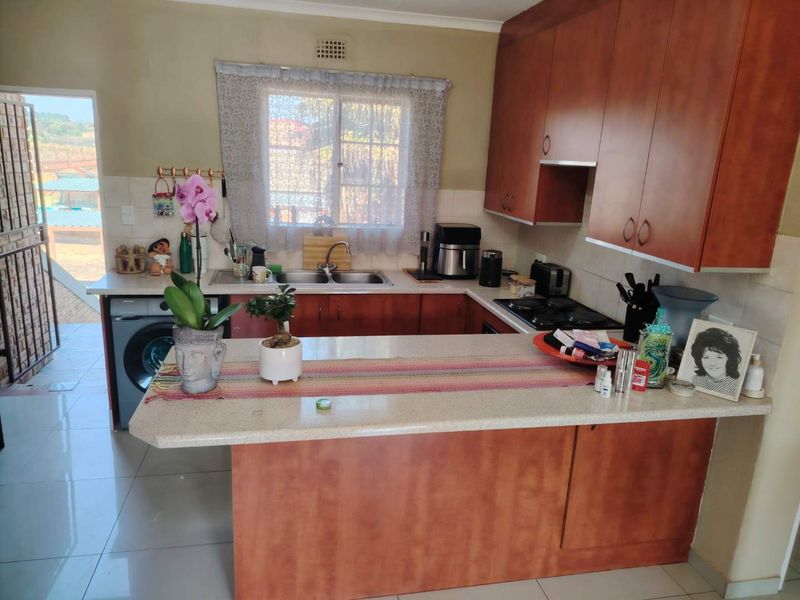 Functional kitchen featuring wood-look cabinetry, stone-effect countertops, a double stainless steel sink, and a built-in gas hob with tiled splashbacks.