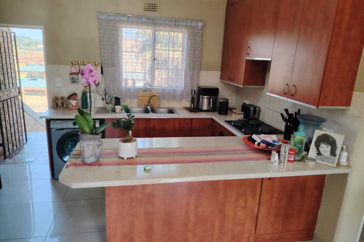 Functional kitchen featuring wood-look cabinetry, stone-effect countertops, a double stainless steel sink, and a built-in gas hob with tiled splashbacks.