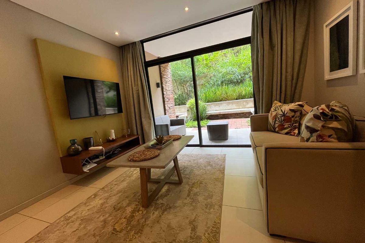 Modern living room featuring large sliding glass doors that open onto a private patio, providing seamless indoor-outdoor flow and natural light.