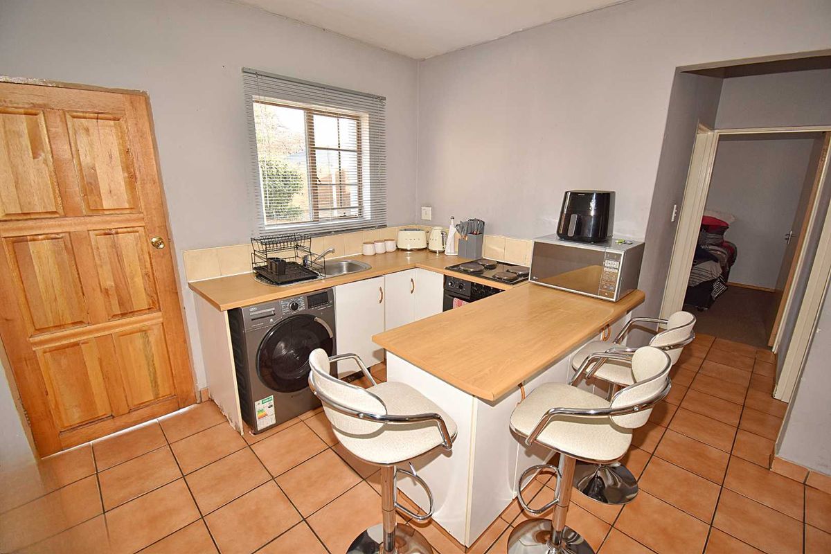 Compact kitchen featuring built-in cabinetry, laminate countertops, integrated hob and oven, and tiled flooring, offering a functional layout for daily meal preparation.