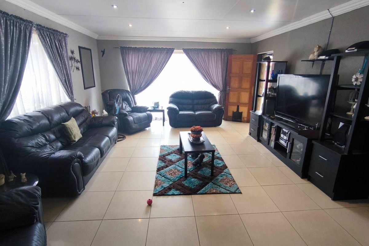 Spacious living room featuring large format floor tiles, recessed downlighting, and crown molding, providing a comfortable and functional family living area.