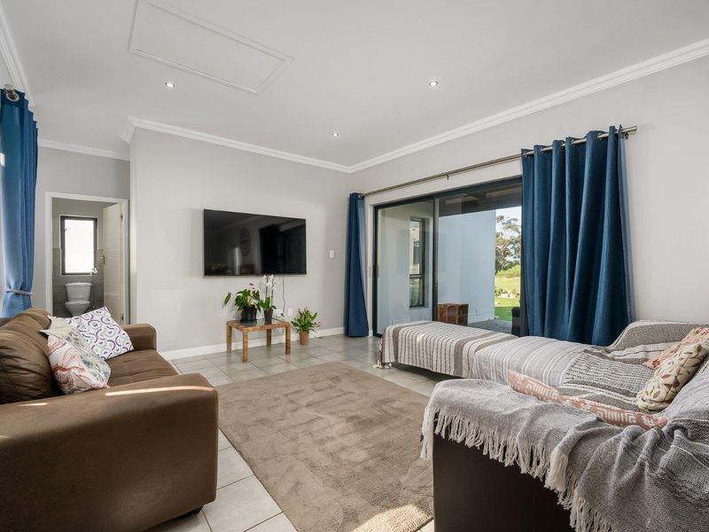 A bright living room featuring tiled flooring, recessed downlights, and large sliding glass doors that provide access to the outdoor patio area.