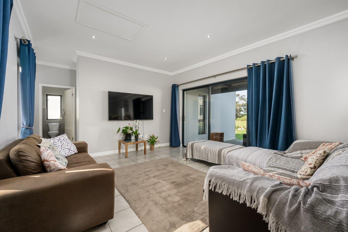 A bright living room featuring tiled flooring, recessed downlights, and large sliding glass doors that provide access to the outdoor patio area.
