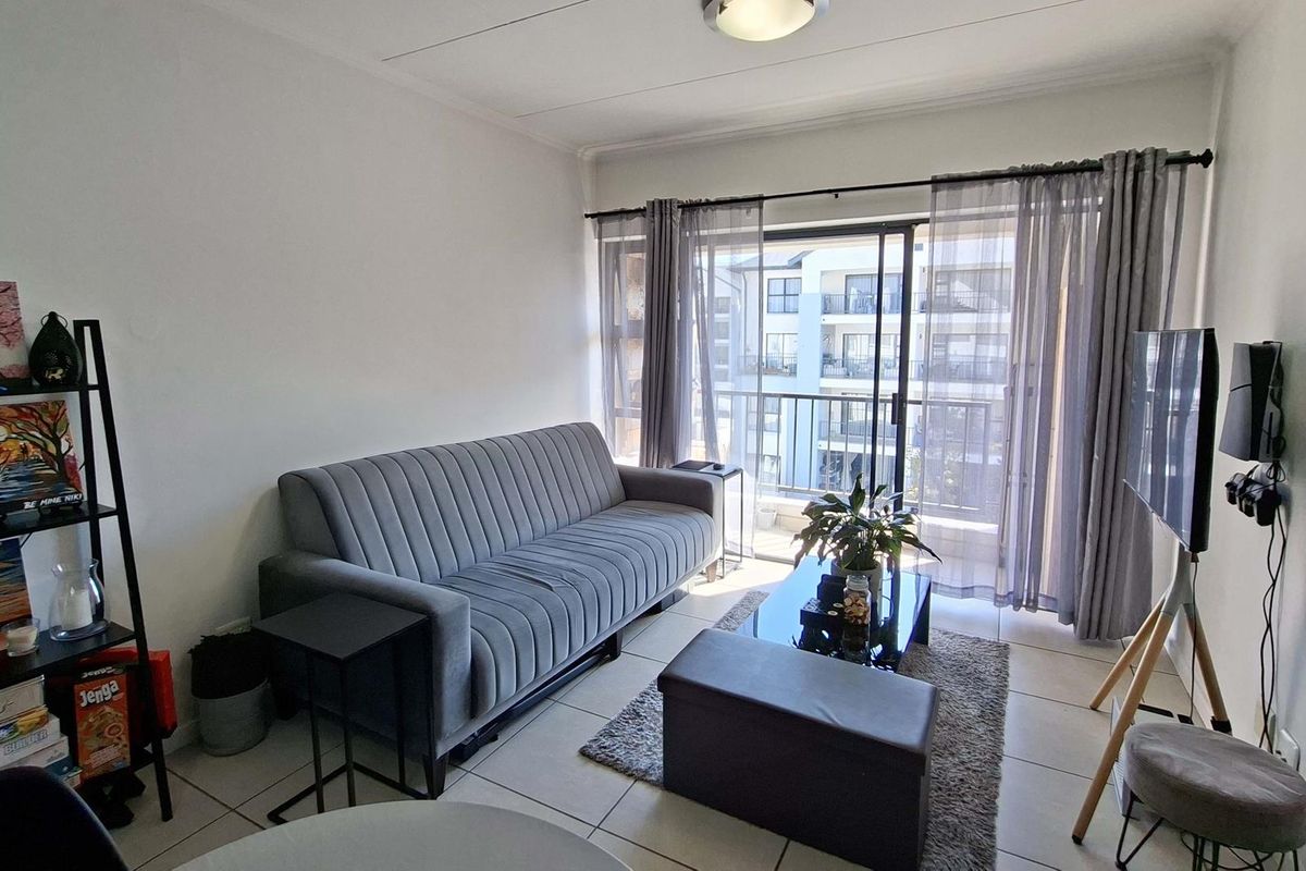 A functional living room featuring tiled flooring and a large sliding glass door that provides access to an outdoor balcony area.