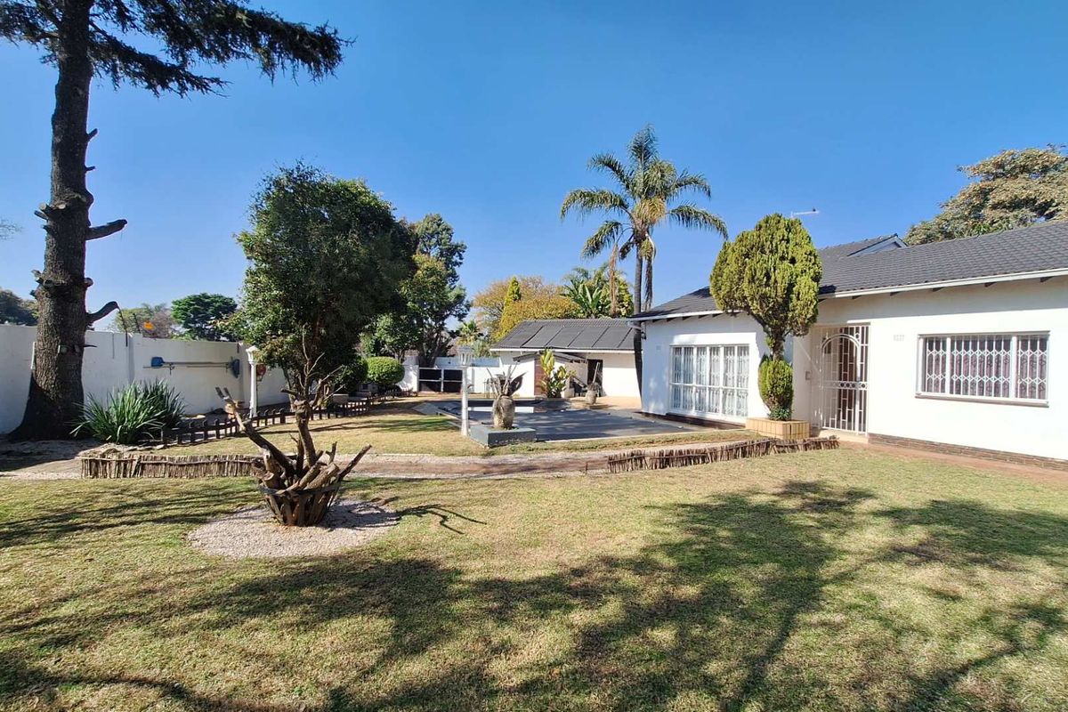 A spacious rear garden featuring a well-maintained lawn, paved patio area, and secure perimeter wall, providing a private outdoor space for the property.