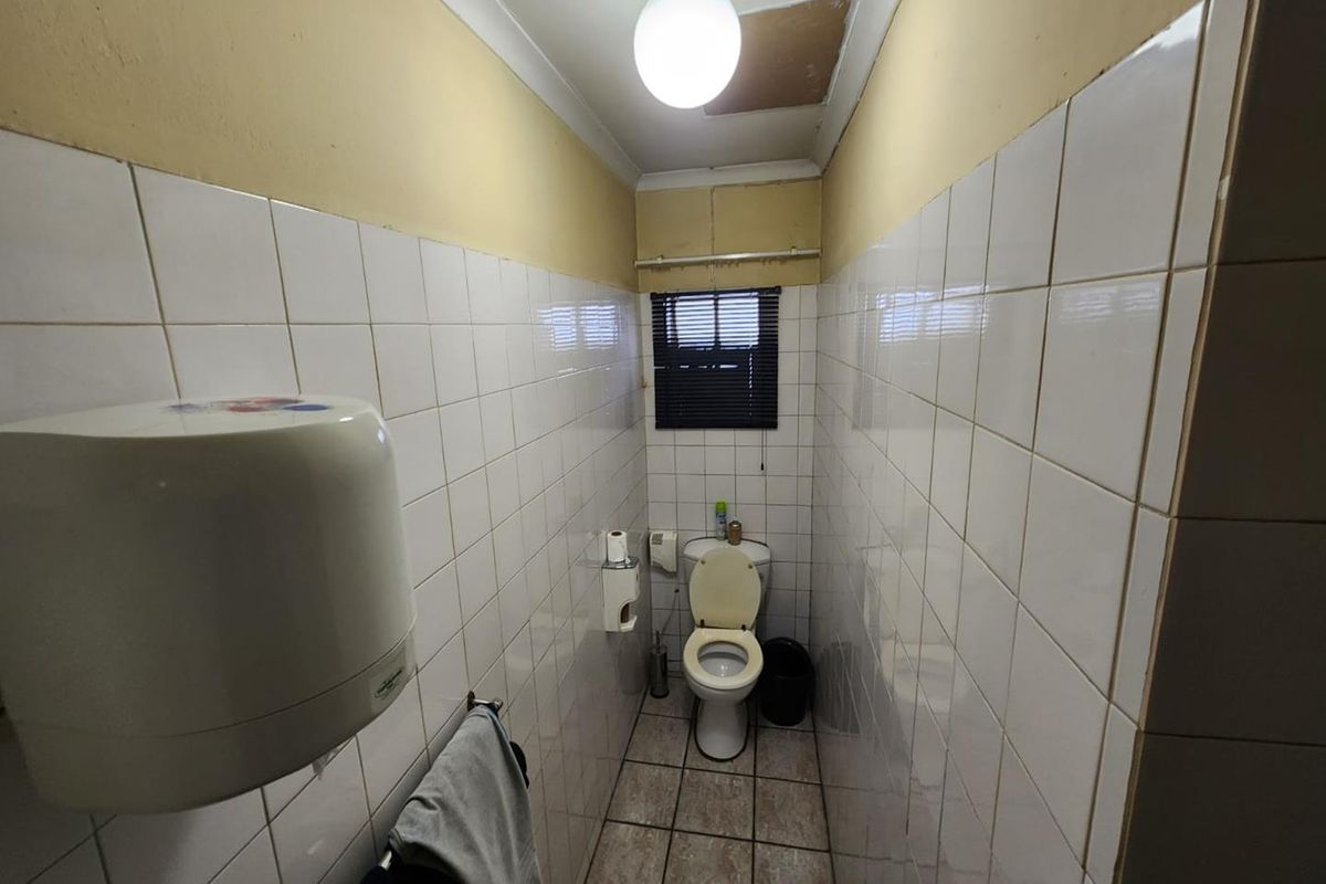 A compact, functional restroom featuring tiled walls and flooring, equipped with a standard toilet and wall-mounted paper dispenser.