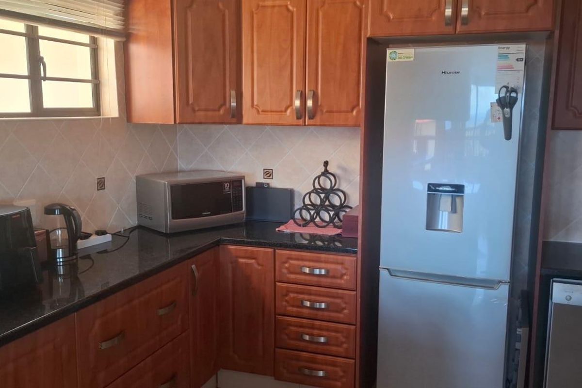 A functional kitchen featuring dark granite countertops, wooden cabinetry, and integrated space for a refrigerator and dishwasher.