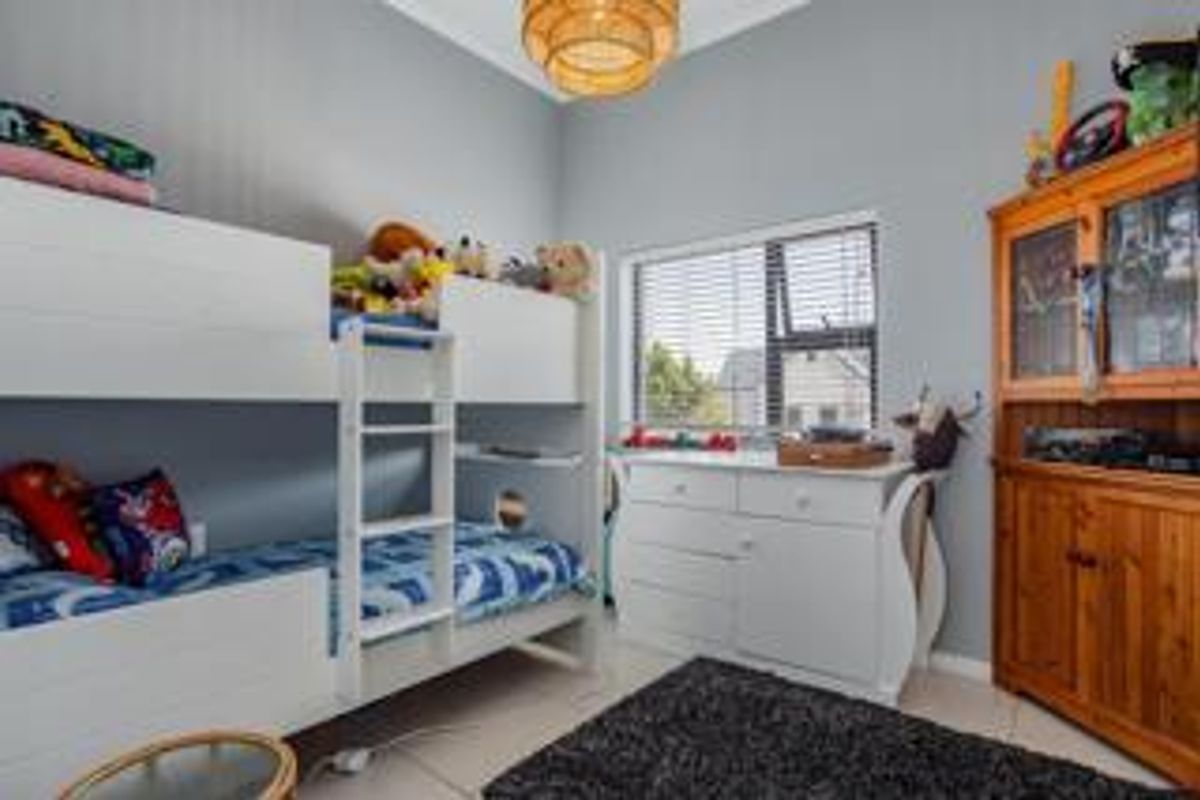 A well-maintained bedroom featuring neutral wall tones, tiled flooring, and a large window providing natural light.